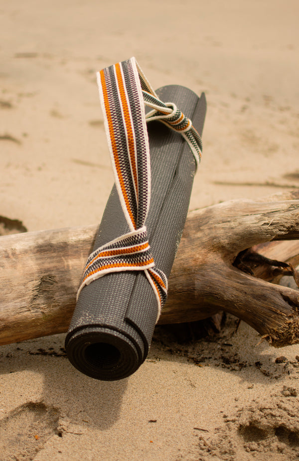 Yoga mat and Catalina strap sat on a large piece of wood on the beach