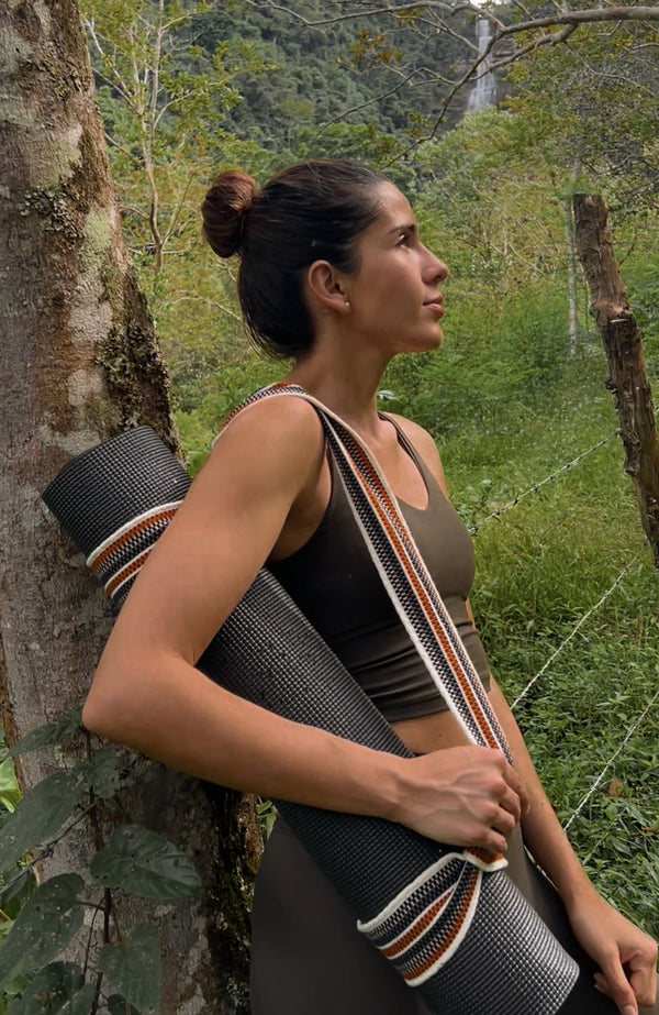 Close up of a woman carrying a yoga mat and Catalina strap over her shoulder