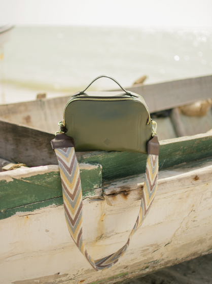 The Olive Urban Safari handbag sitting on the side of an old wooden boat